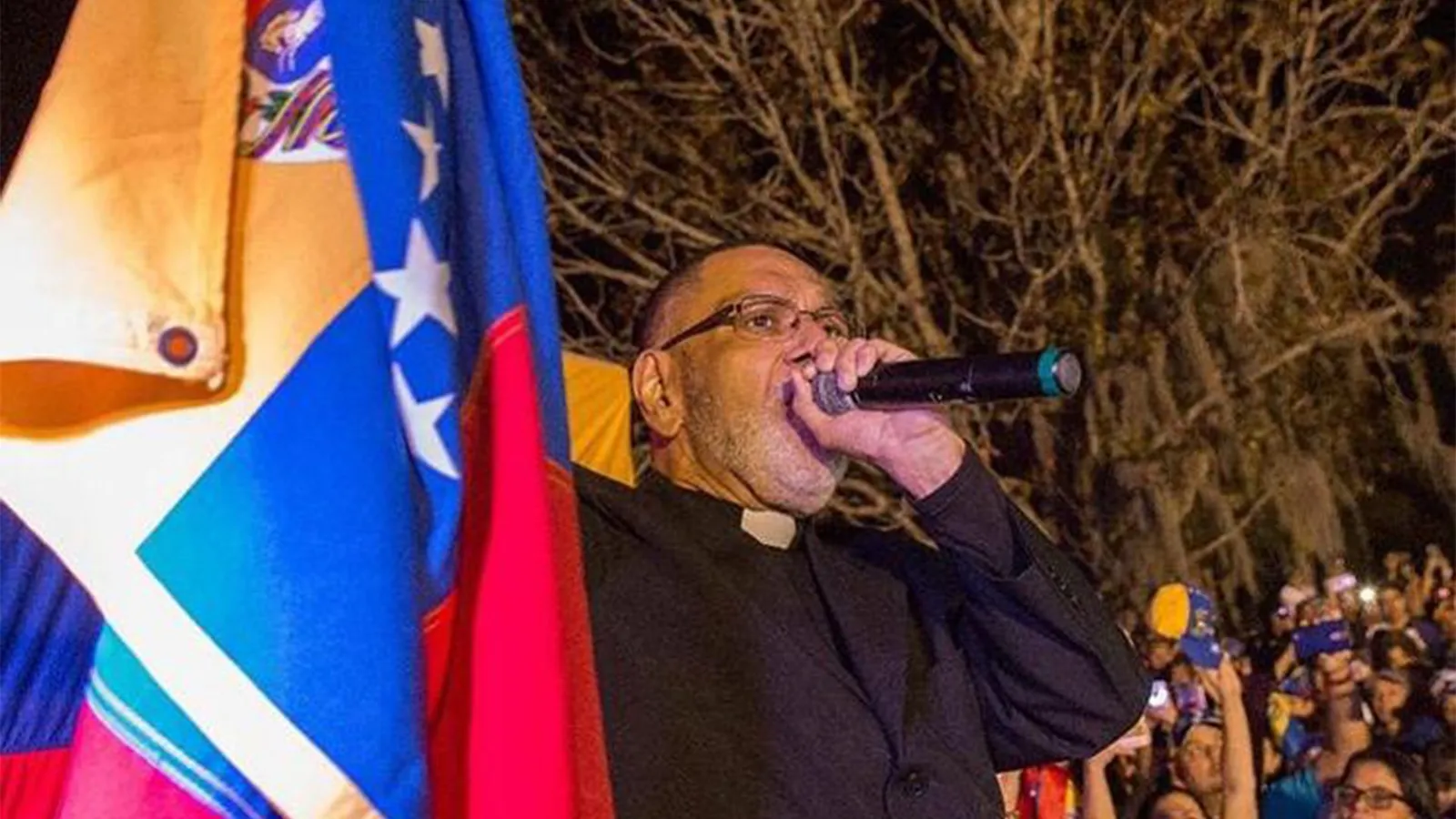 Padre José Palmar predicando junto a la bandera de Venezuela